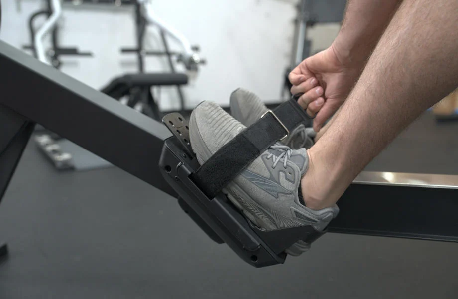 Strapping into the pedals on a YOSUDA Dragon Fly Rowing Machine