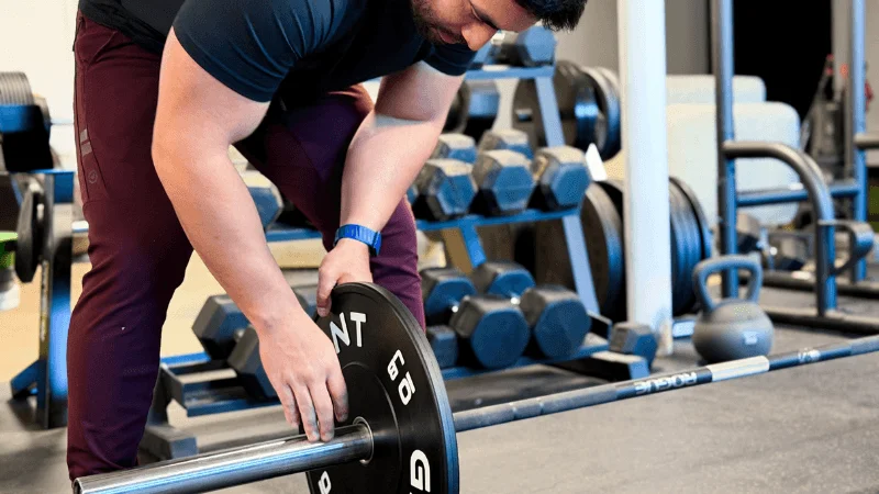 Our tester adding some GIANT Lifting Base Bumper Plates to their barbell before a workout