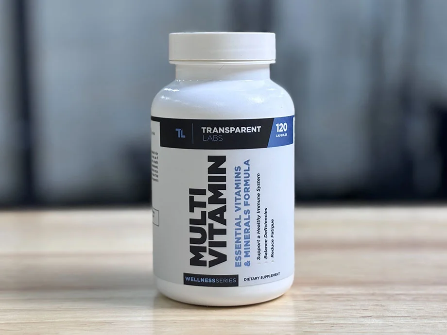 A bottle of Transparent Labs Multivitamin on a table with a blurry gray background