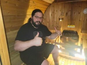 man sitting in almost heaven barrel sauna
