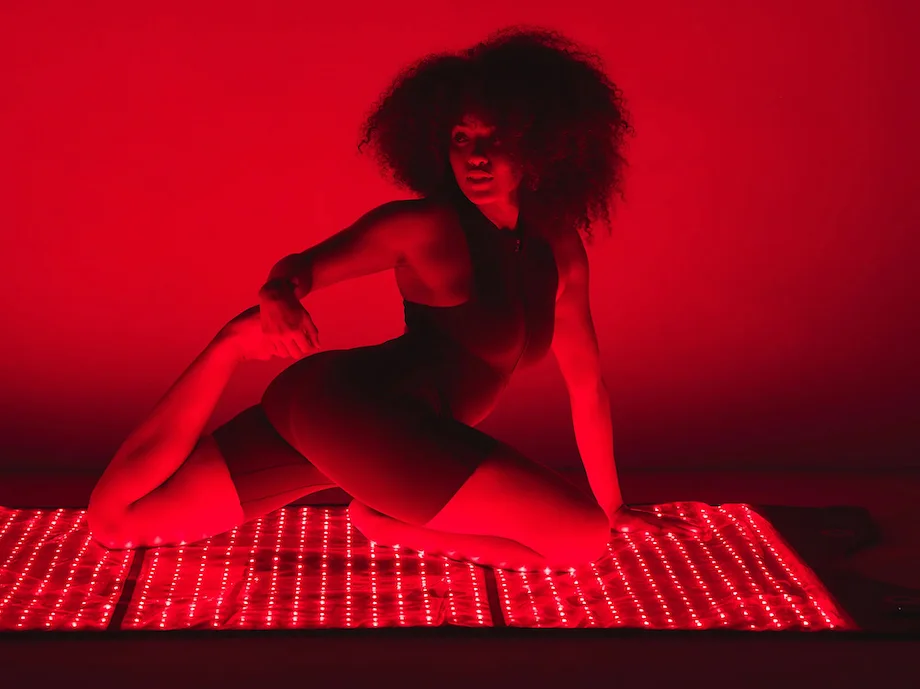 A woman stretching on the HigherDOSE Red Light Therapy mat