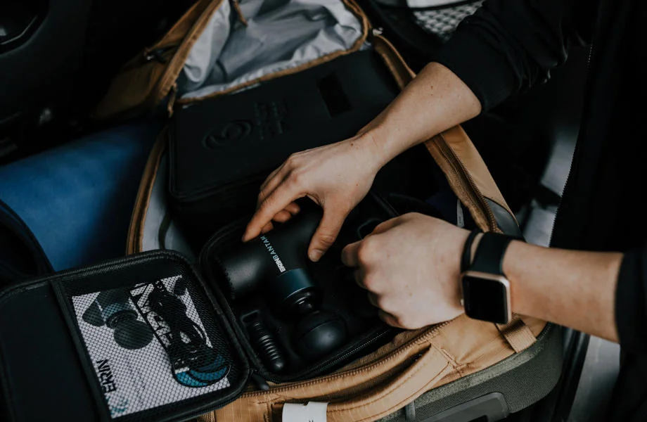 A person lifts an Ekrin Bantam mini-massage gun from it's carrying case.