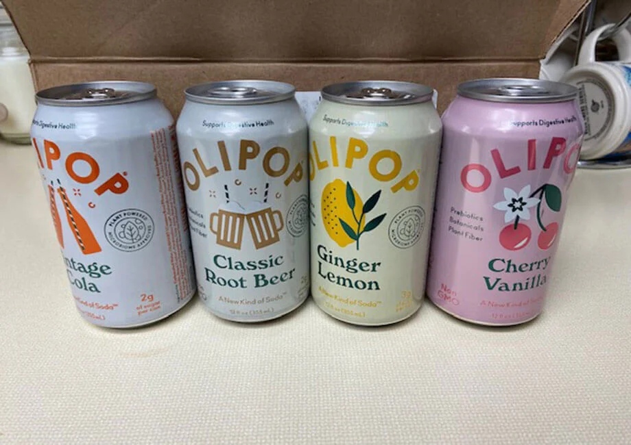 Vintage Cola, Classic Root Beer, Ginger Lemon, and Cherry Vanilla flavors of OLIPOP lined up next to each other