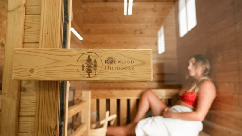 Our tester seen through the glass doorway of the Redwood Outdoors Thermowood Cabin sauna