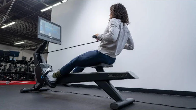 A woman using the NordicTrack RW900 rowing machine.