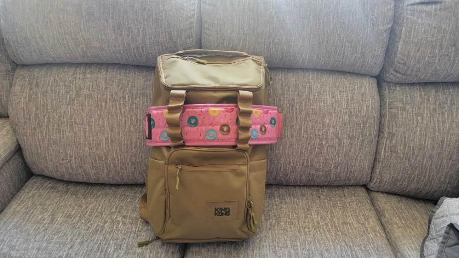 A KNKG CORE Gym Backpack rests on a couch with a belt