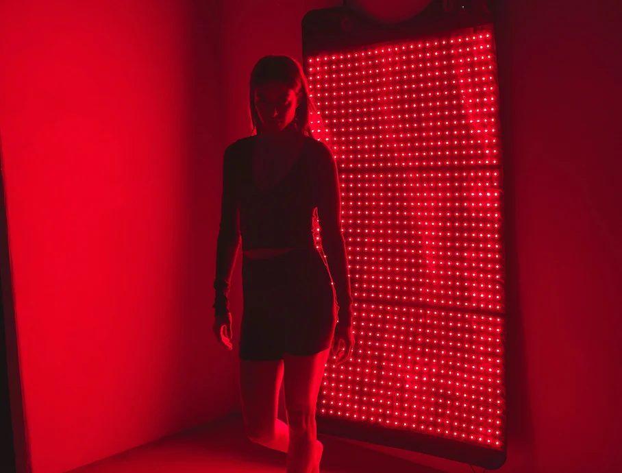 A woman standing in front of the HigherDOSE Red Light Therapy Mat