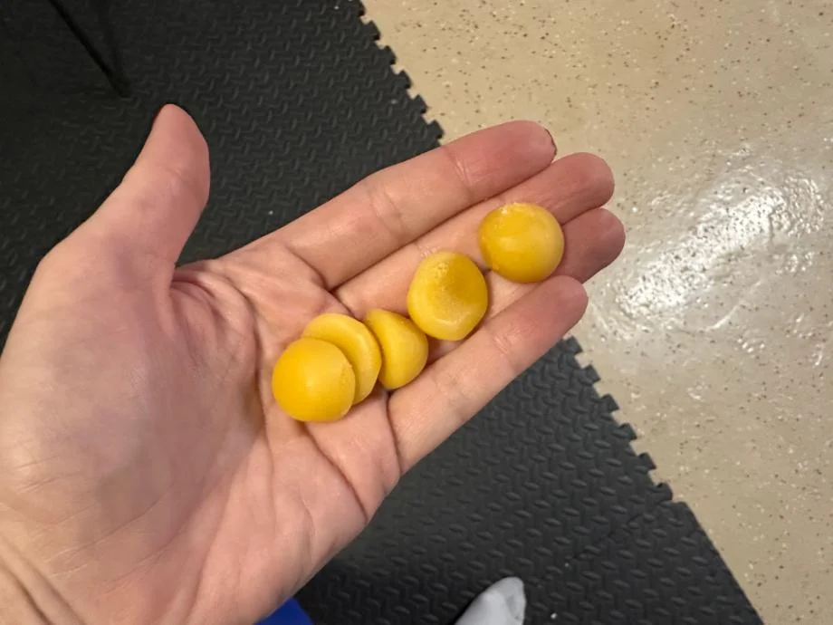 A hand holds out five Legion Creatine Gummies, the serving size