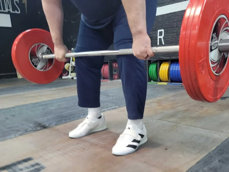 A person lifting weights with adidas Adipower III gym shoes