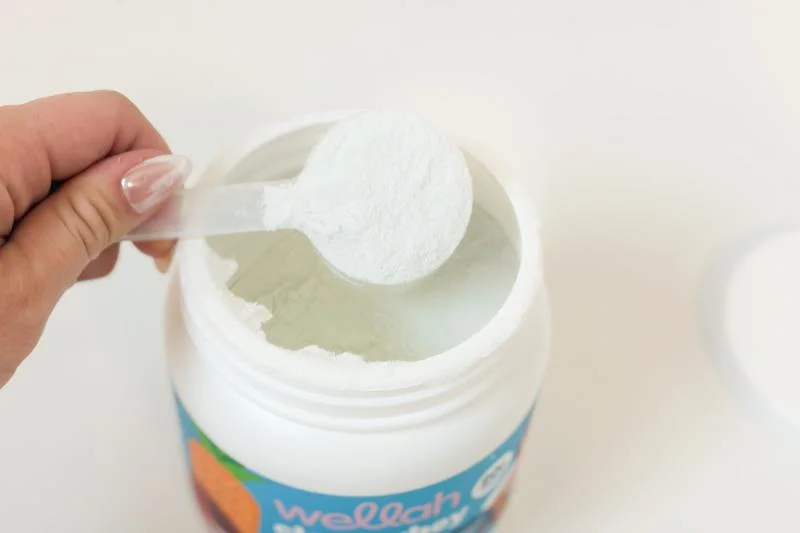 Holding a scoop of Wellah Clear Whey Protein
