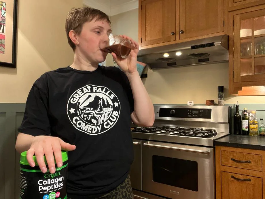 A woman drinks Orgain Collagen Peptides from a glass.