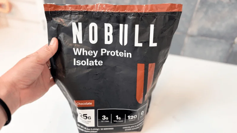 ggr-nobull-grass-fed-whey-protein-isolate-front-container-label Our tester holding an open container of NOBULL Grass-Fed Whey Protein Isolate