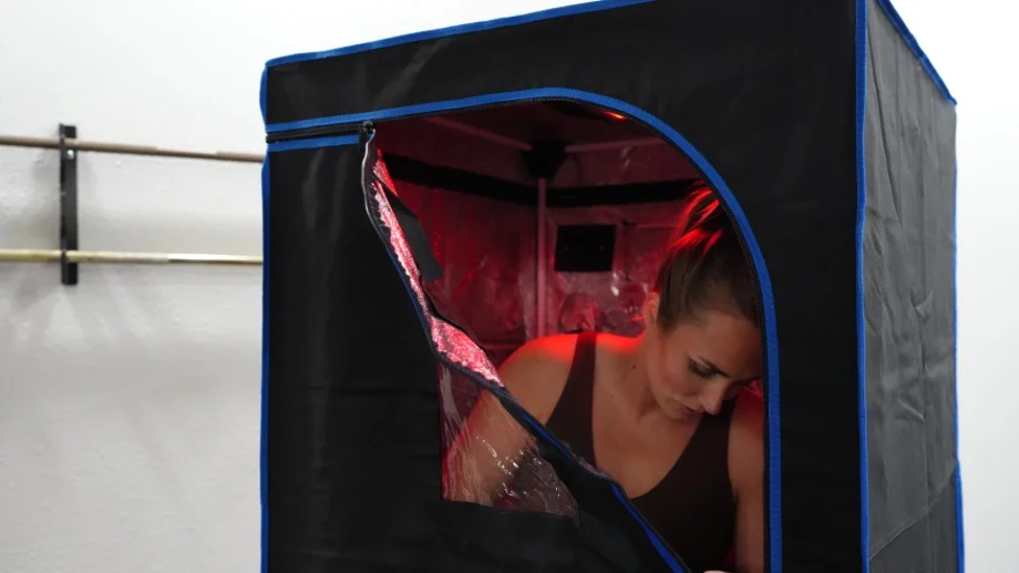 A woman is shown zipping the door shut on a SereneLife Portable Full Size Infrared Sauna.