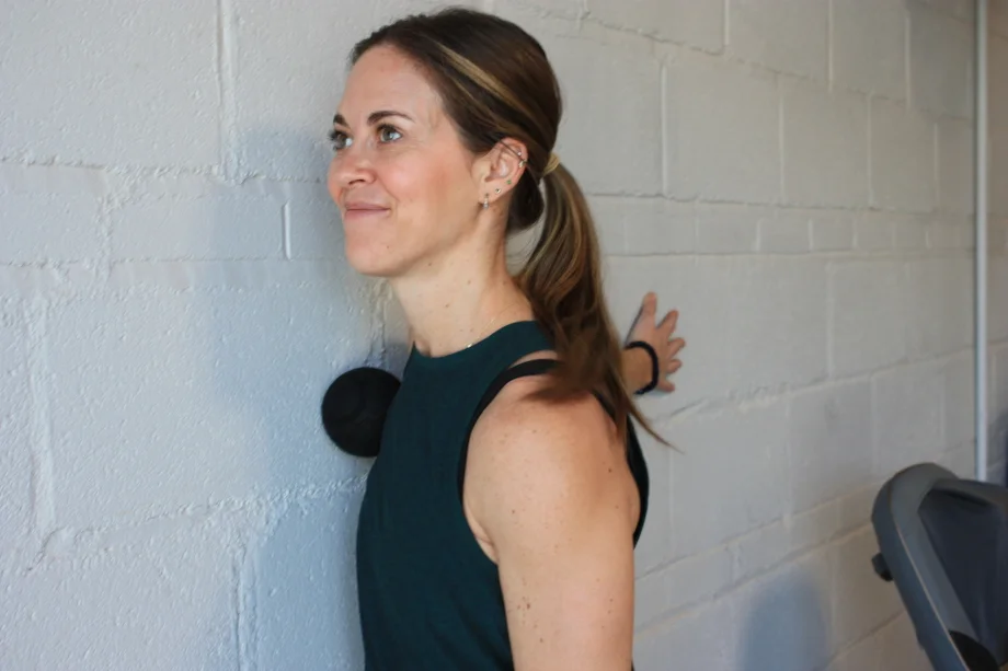 Woman using the Therabody Wave Solo on her chest and shoulder