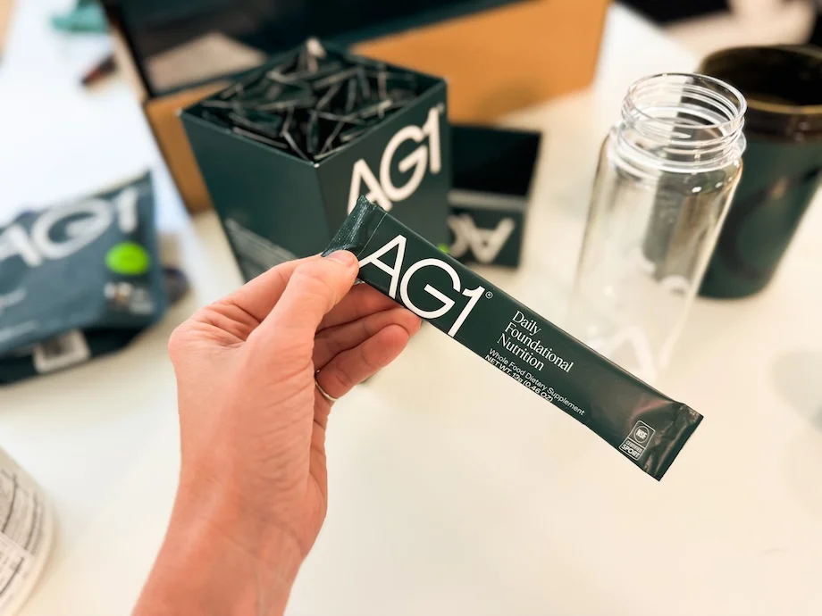 Woman holding a travel packet of Athletic Greens AG1