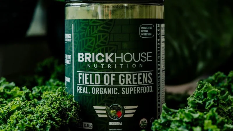 A close-up view of a container of Brickhouse Nutrition FIeld of Greens