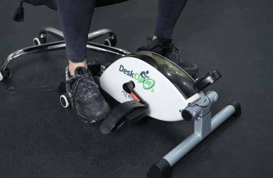 Our tester getting their feet secured into the DeskCycle 2 Under Desk Exercise Bike And Pedal Exerciser