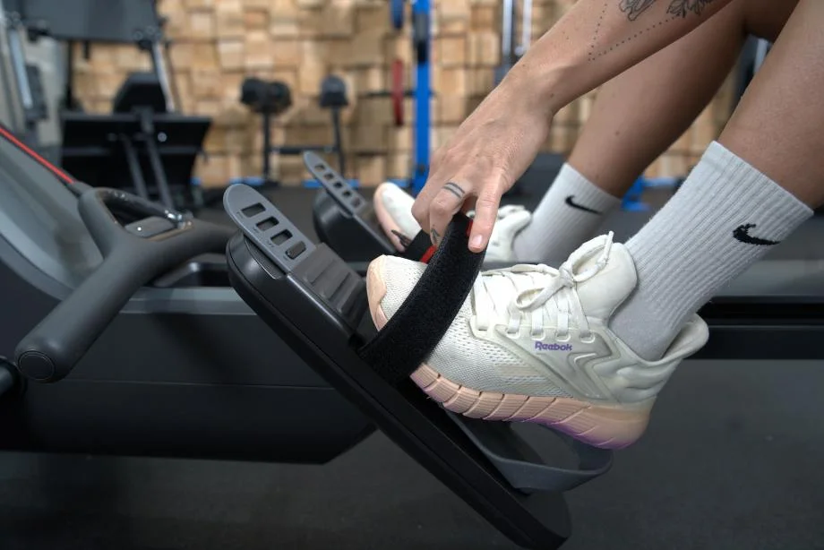 A woman adjusts the foot straps on the Peloton Row