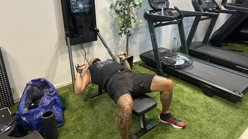 A person bench pressing with the Tonal 2 Smart Home Gym.