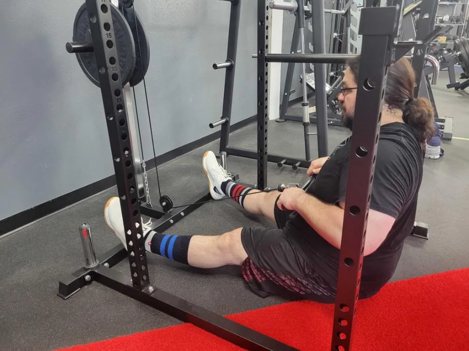 A man performing seated low rows with the Giant Lifting Garage Gym Rack 2.0 with lat and low row attachments