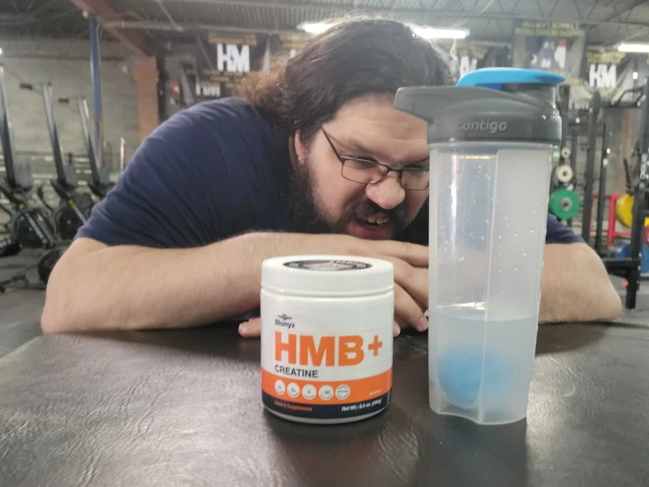 Caine Wilkes looks at a shaker cup filled with BLonyx HMB+ Creatine