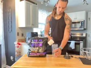 person putting muscle tech mass gainer in cup 1