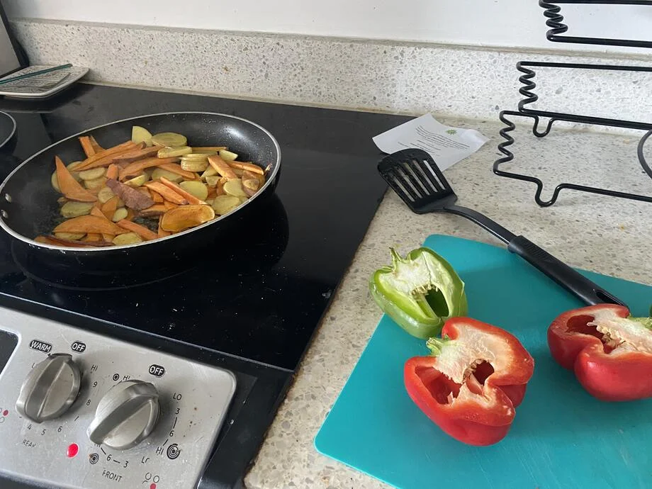 An image of a Sunbasket meal kit being prepared with veggies being chopped and cooked