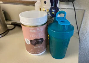 tone it up protein product next to shaker bottle
