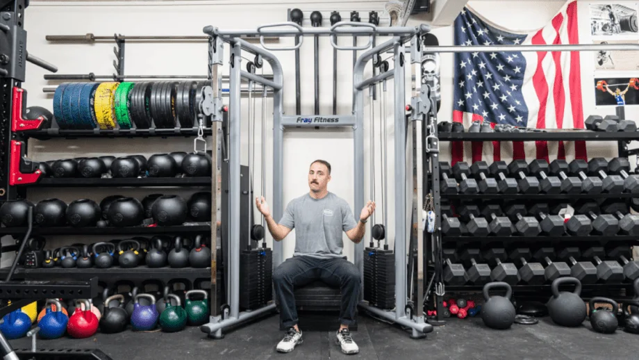 Image of Coop sitting in front of a functional trainer for the cover image of the best home gyms