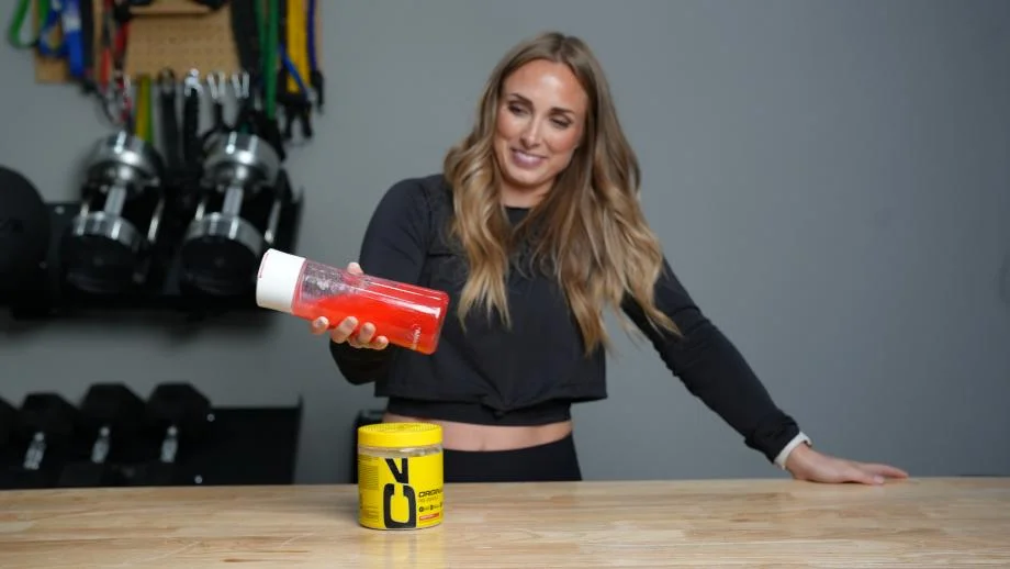 A woman shakes a bottle of water mixed with C4 Pre-Workout