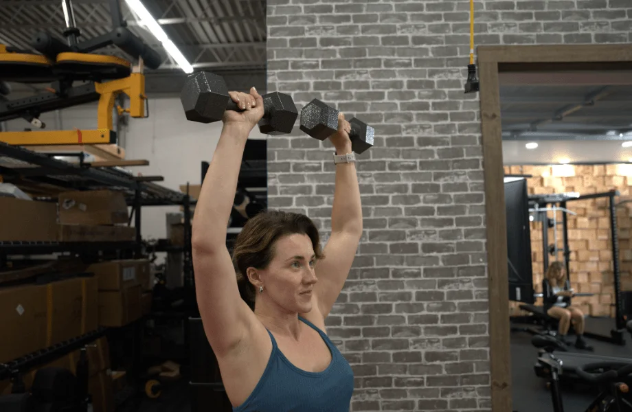 Our tester performing an overhead press with CAP Cast Iron Hex Dumbbells