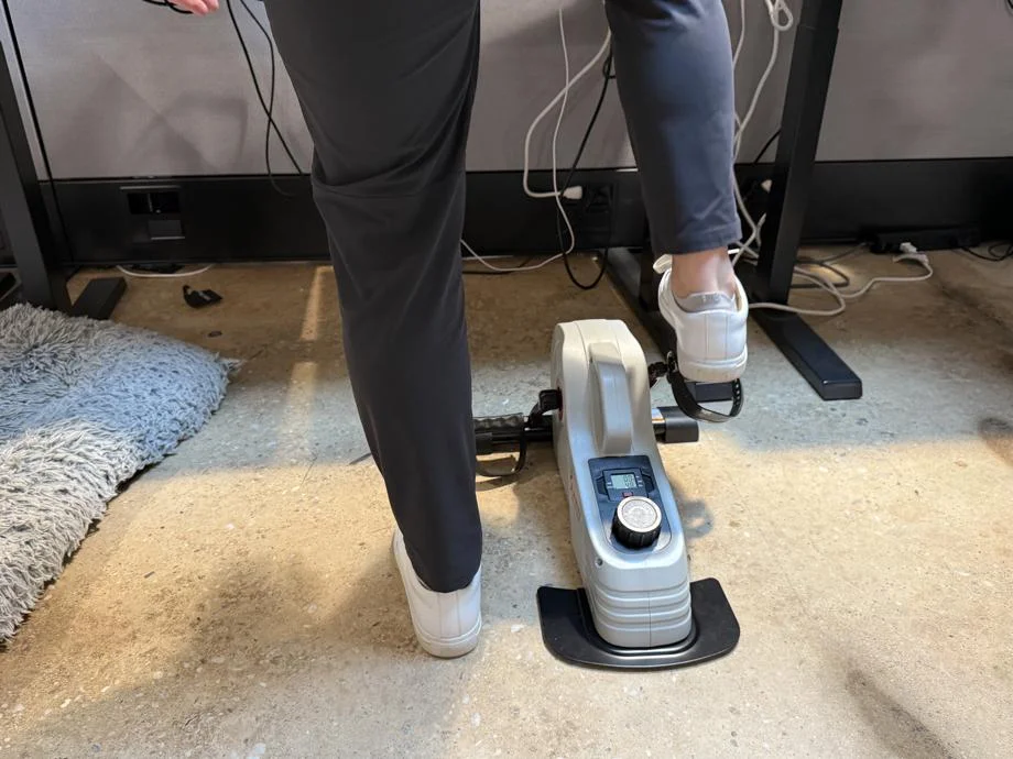 A person steps onto the pedals of a Sunny Health & Fitness Magnetic Mini Exercise Bike