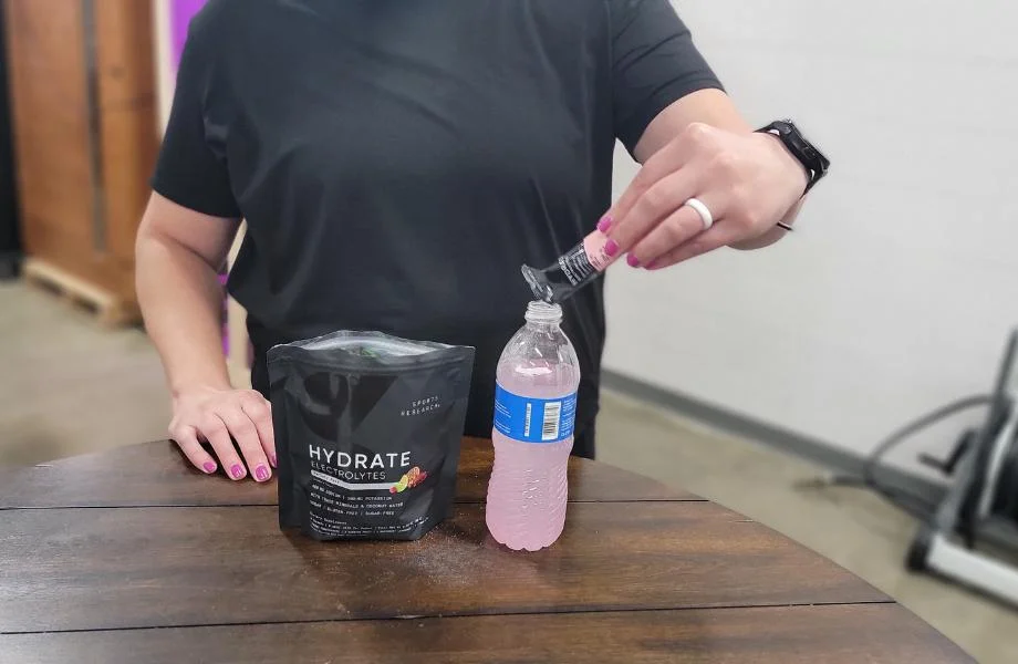 A person pouring Sports Research Hydrate into a water bottle