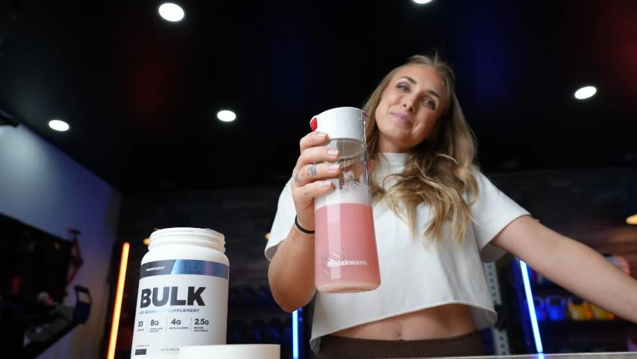 A woman holds a mixed pre-workout drink of Transparent Labs BULK