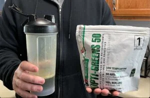 man holding bag of opti greens 50 and shaker 1