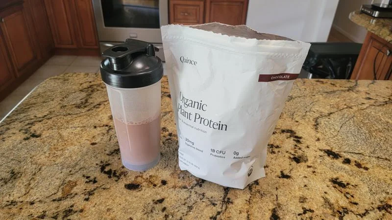 A Quince Organic Plant Protein shake next to the opened bag