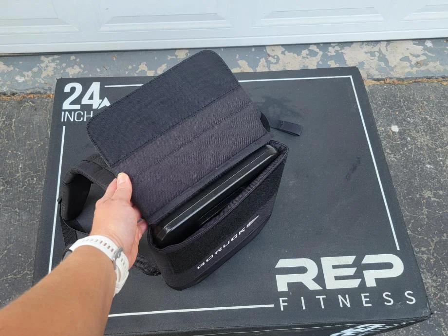 A person holds open the GORUCK Ruck Plate Carrier 3.0 open, showing the weight plate inside