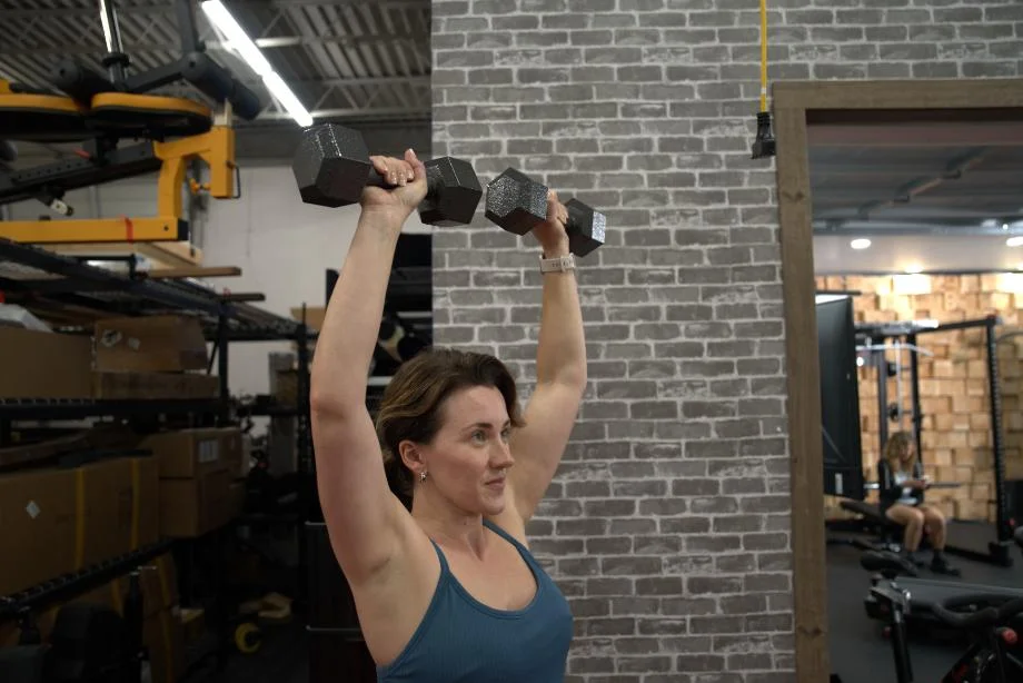 A woman lifting Cap Iron Hex Dumbbells overhead