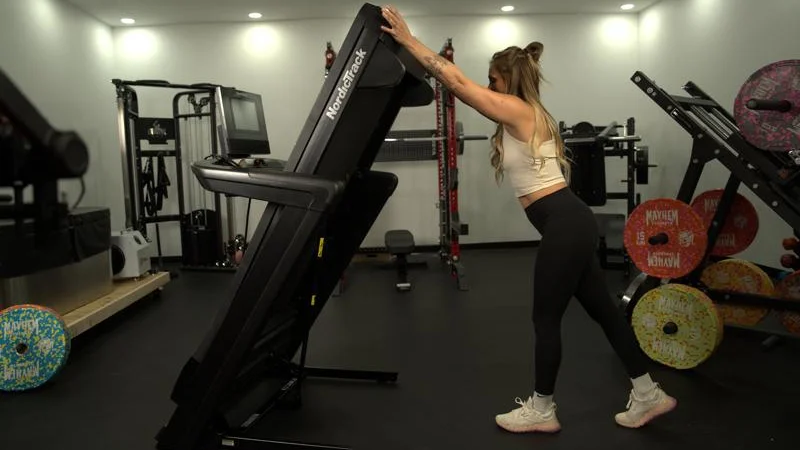 Side view as a person folds up a NordicTrack Commercial 1250 treadmill.