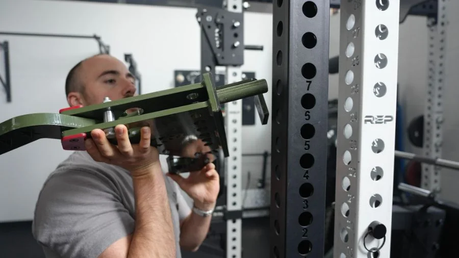 Man placing a rack attachment on a power rack