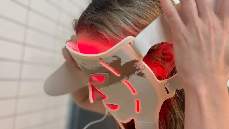 A person putting on the Renpho LED Light Therapy Mask.