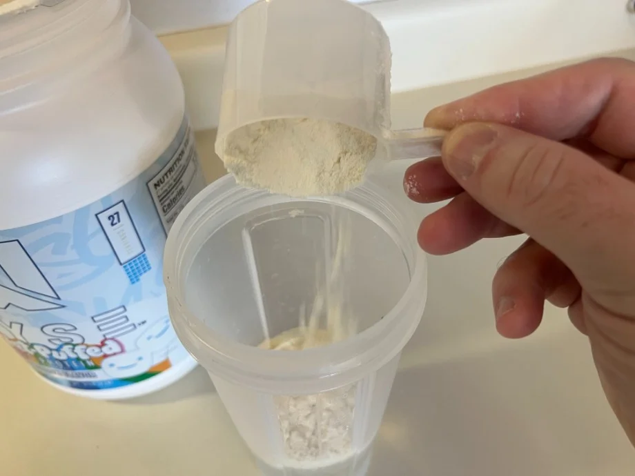 A scoop of RYSE Loaded Protein Powder is being poured.