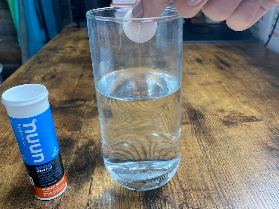 Person about to drop a Nuun Sport tablet into a glass of water