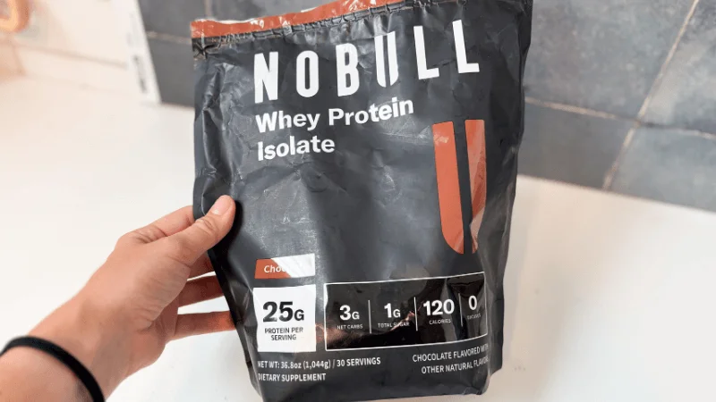 Our tester reading the macronutrients counts on the front of a NOBULL Grass-Fed Whey Protein Isolate container