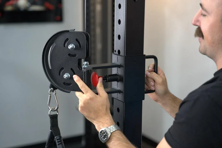Man adjusting the trolley height on the uprights of the Body-Solid Functional Trainer Rack