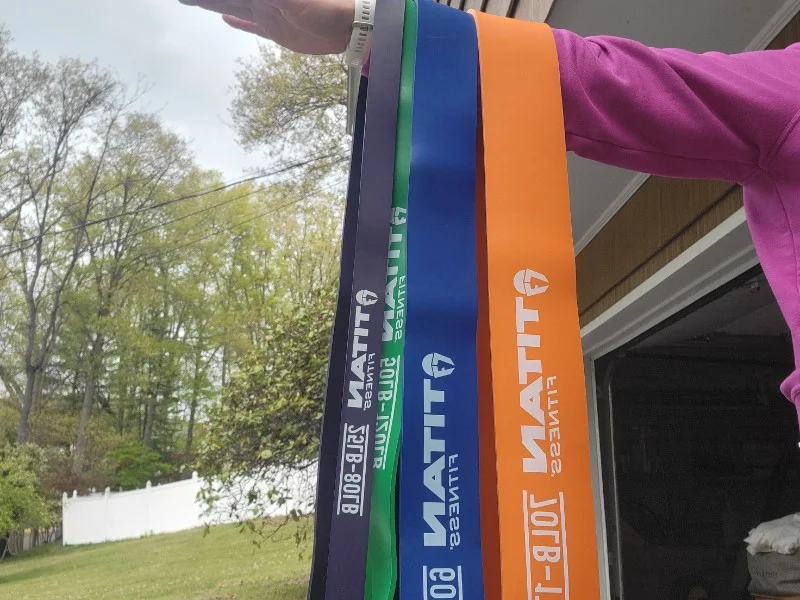 A set of Titan Fitness Heavy Resistance Bands hanging from a person's arm