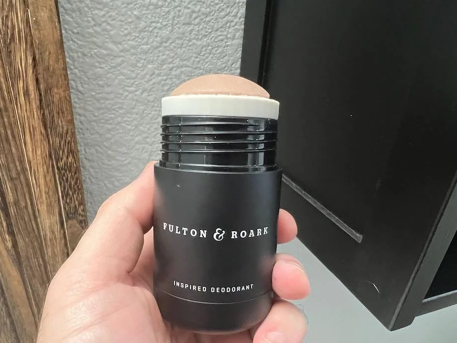 A hand holds up a tube of Fulton & Roark Calle Ocho Dedorant