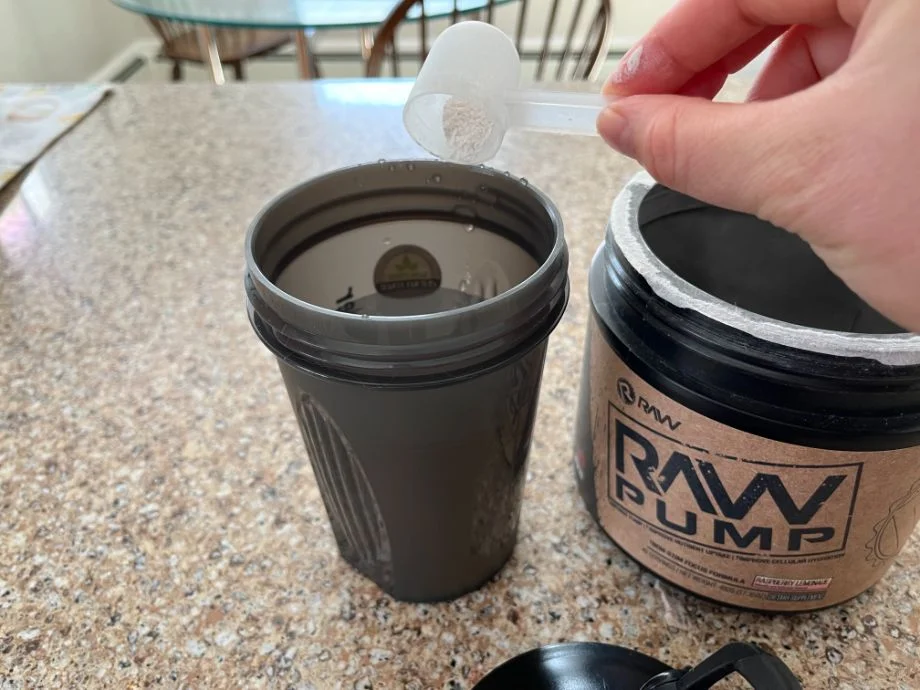 Stim-free RAW Pump Pre-workout being scooped into a shaker cup