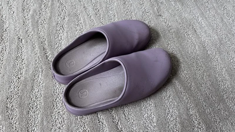 A two month old pair of Lululemon SwayDay Mule recovery shoes on a grey patterned carpet.