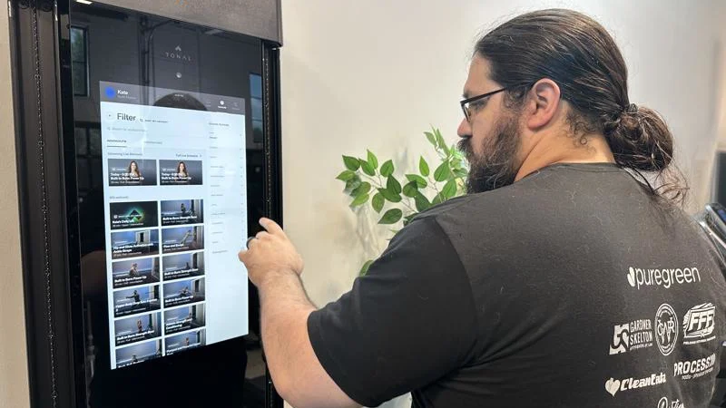 Olympian Caine Wilkes scrolls through workouts on the Tonal 2 Smart Home Gym.